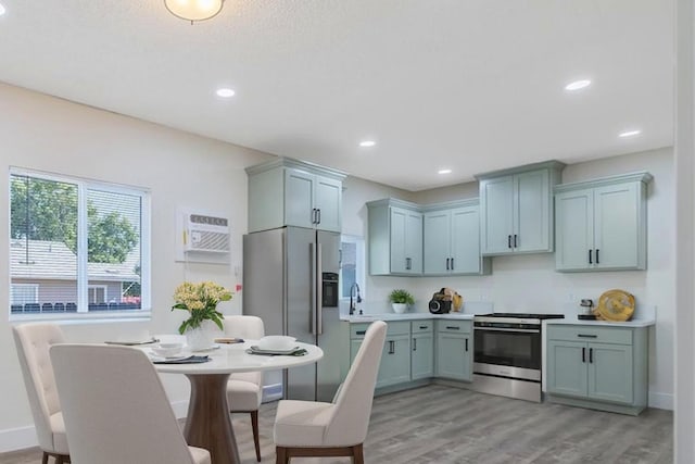 221 N Orchard St, Fresno, CA 93701 - kitchen with stainless steel appliances, a wall unit AC, light wood finished floors, light countertops, and recessed lighting