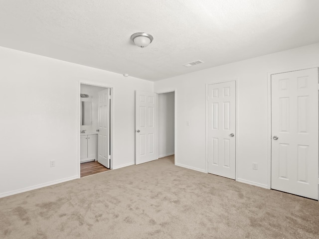 2557 Jackson St, Selma, CA 93662 - unfurnished bedroom featuring carpet flooring, ensuite bath, and a textured ceiling