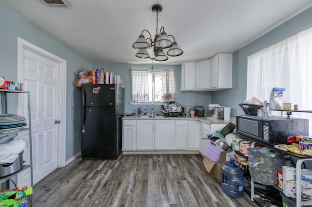 448 E Tuolumne St, Fresno, CA 93706 - kitchen with black appliances, a chandelier, white cabinetry, and wood finished floors