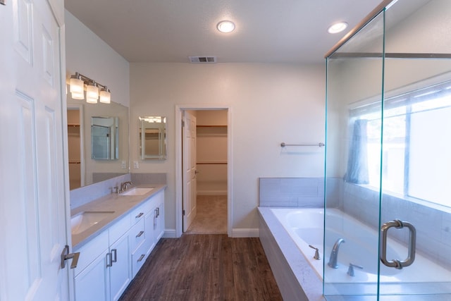 1963 Rialto Ct, Clovis, CA 93611 - bathroom featuring double vanity, a walk in closet, a bath, wood finished floors, and recessed lighting