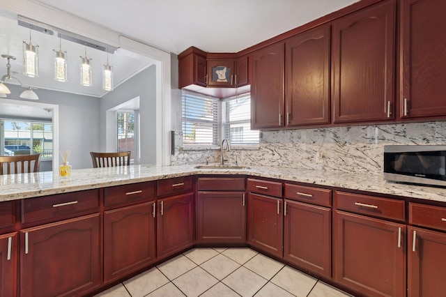 3924 E Iowa Ave, Fresno, CA 93702 - kitchen with stainless steel microwave, light stone counters, light tile patterned flooring, decorative backsplash, and reddish brown cabinets