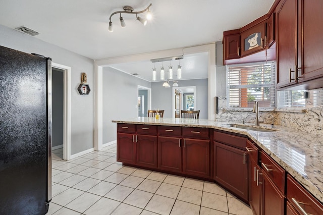 3924 E Iowa Ave, Fresno, CA 93702 - kitchen with light tile patterned floors, freestanding refrigerator, reddish brown cabinets, a peninsula, and tasteful backsplash