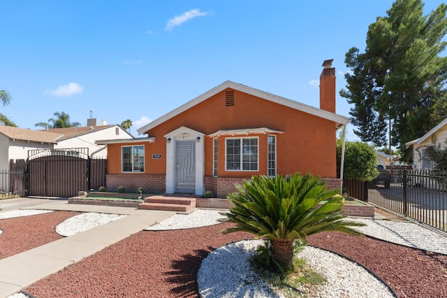 3924 E Iowa Ave, Fresno, CA 93702 - bungalow-style home with a gate, brick siding, a chimney, stucco siding, and driveway