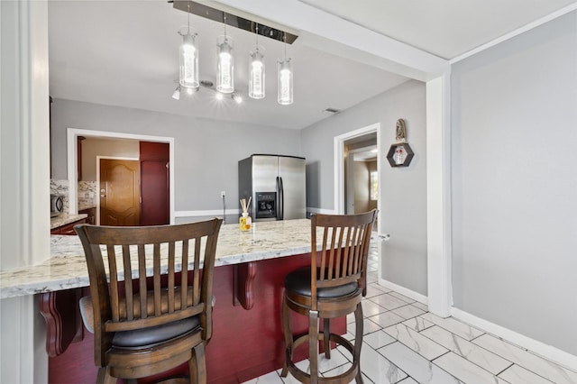 3924 E Iowa Ave, Fresno, CA 93702 - kitchen with stainless steel fridge, light marble finish flooring, a breakfast bar, pendant lighting, and light stone counters