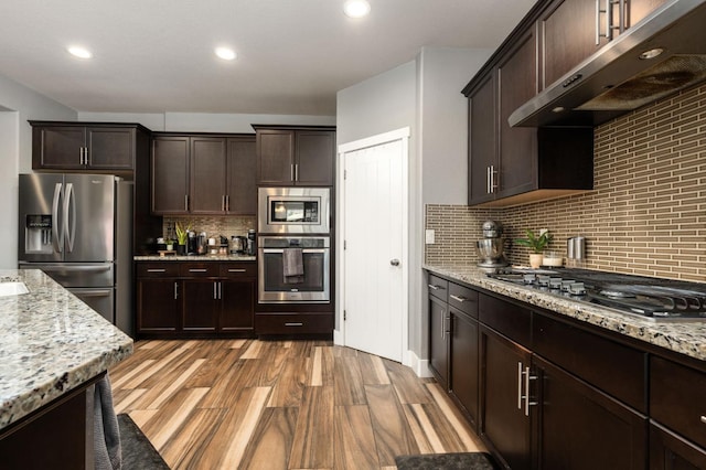 1397 N Redington Ave, Clovis, CA 93619 - kitchen with stainless steel appliances, under cabinet range hood, wood finished floors, dark brown cabinetry, and recessed lighting