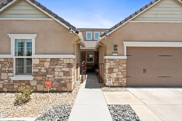 1397 N Redington Ave, Clovis, CA 93619 - property entrance with stone siding, driveway, an attached garage, and stucco siding