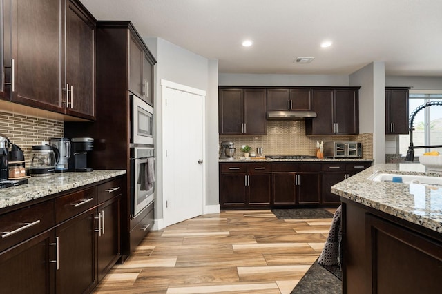 1397 N Redington Ave, Clovis, CA 93619 - kitchen with stainless steel appliances, backsplash, under cabinet range hood, light stone countertops, and recessed lighting