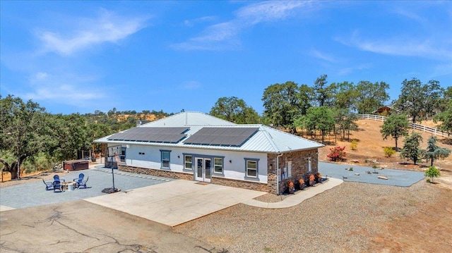34503 Backbone Rd, Auberry, CA 93602 - back of property featuring a patio area, solar panels, a hot tub, stone siding, and stucco siding