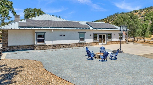 34503 Backbone Rd, Auberry, CA 93602 - back of house featuring french doors, stucco siding, stone siding, and roof mounted solar panels