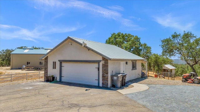 34503 Backbone Rd, Auberry, CA 93602 - view of side of property with stone siding, driveway, stucco siding, a metal roof, and a garage