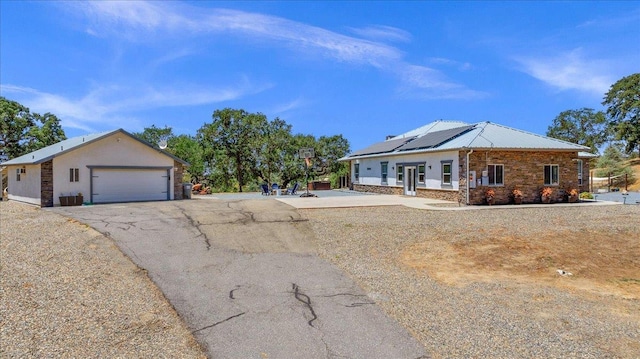34503 Backbone Rd, Auberry, CA 93602 - view of front of home featuring stone siding, a garage, solar panels, and a metal roof