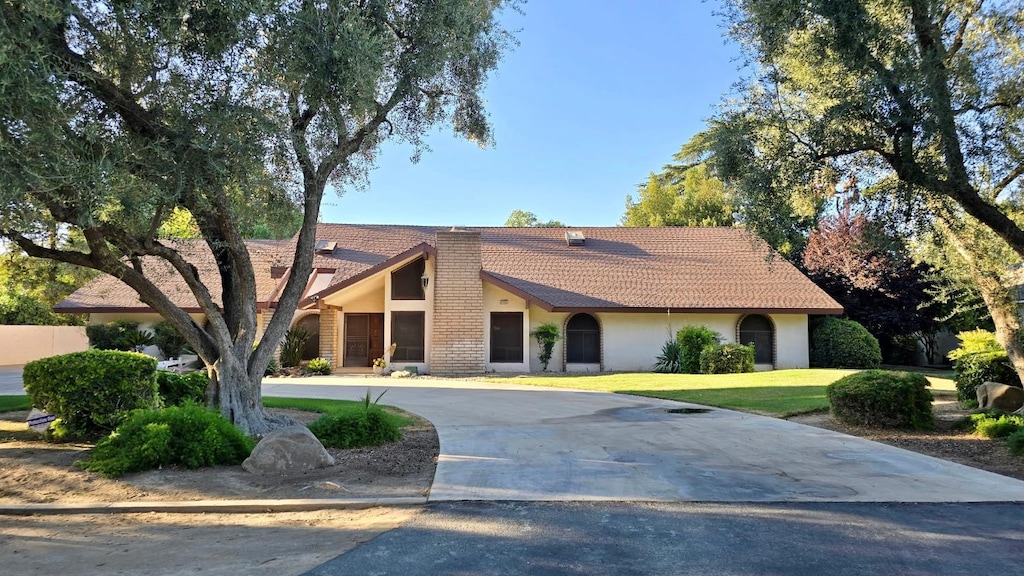5433 E Geary St, Fresno, CA 93727 - view of front of home with stucco siding, a tiled roof, a front lawn, and curved driveway