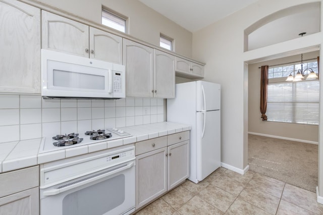 5484 W El Paso Ave, Fresno, CA 93722 - kitchen featuring white appliances, tile counters, tasteful backsplash, a chandelier, and light colored carpet