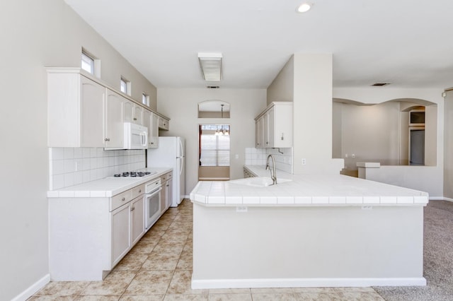 5484 W El Paso Ave, Fresno, CA 93722 - kitchen featuring arched walkways, white appliances, tile counters, and backsplash