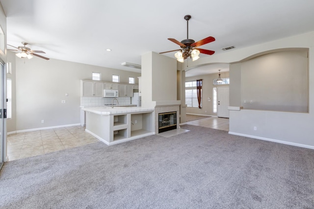 5484 W El Paso Ave, Fresno, CA 93722 - unfurnished living room featuring a ceiling fan, arched walkways, light carpet, recessed lighting, and a tile fireplace