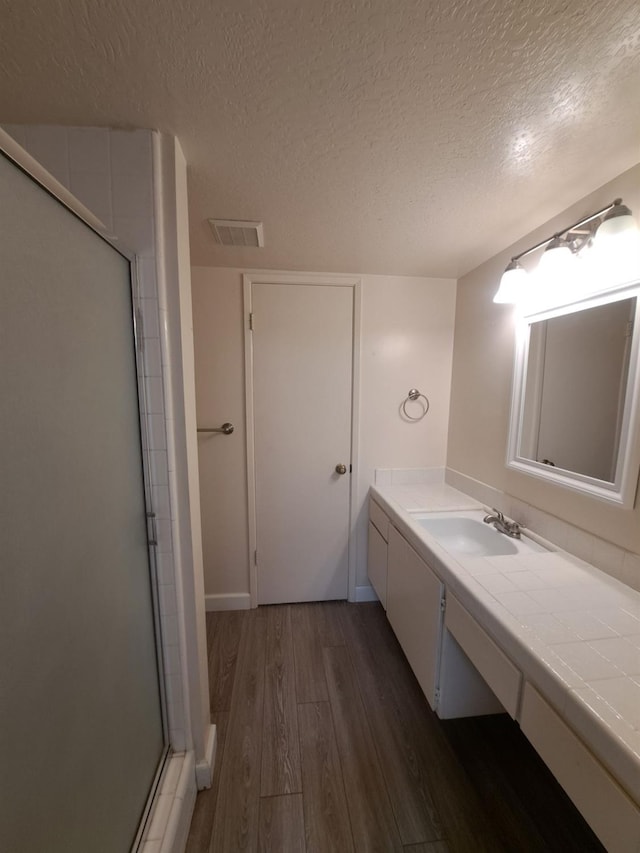 4919 N Millbrook Ave Unit 123, Fresno, CA 93726 - full bath featuring wood finished floors, a shower stall, vanity, and a textured ceiling
