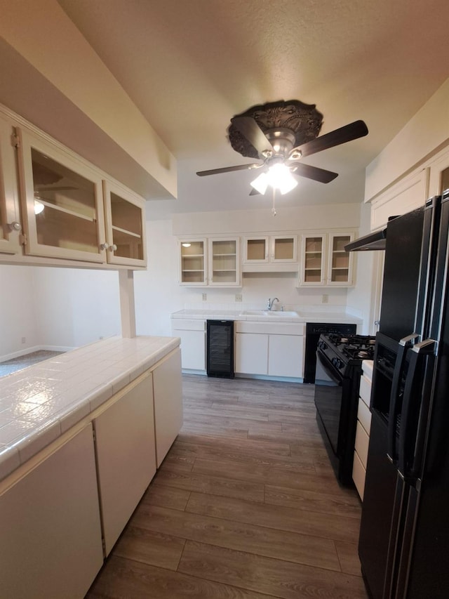 4919 N Millbrook Ave Unit 123, Fresno, CA 93726 - kitchen with black appliances, wine cooler, white cabinets, ceiling fan, and tile counters