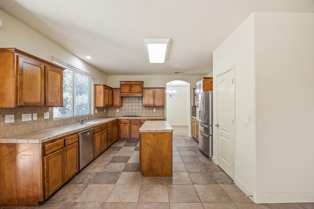 5929 N La Paz Ave, Fresno, CA 93723 - kitchen featuring stainless steel appliances, tile countertops, tasteful backsplash, a kitchen island, and arched walkways