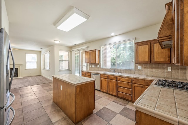 5929 N La Paz Ave, Fresno, CA 93723 - kitchen with stainless steel appliances, backsplash, tile counters, brown cabinetry, and healthy amount of natural light