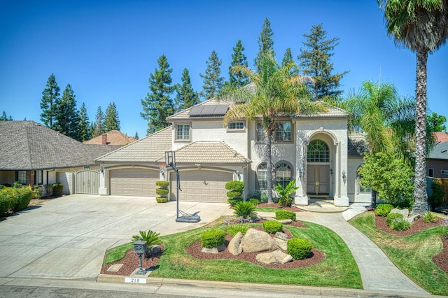 218 W Hubert Ct, Fresno, CA 93711 - mediterranean / spanish-style house with an attached garage, stucco siding, solar panels, concrete driveway, and a tiled roof