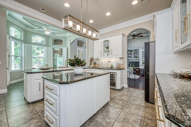 218 W Hubert Ct, Fresno, CA 93711 - kitchen with a ceiling fan, ornamental molding, a peninsula, a kitchen island, and light tile patterned floors