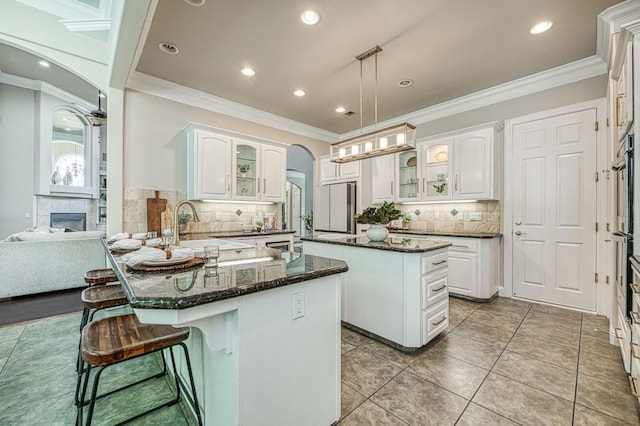 218 W Hubert Ct, Fresno, CA 93711 - kitchen with a peninsula, glass insert cabinets, arched walkways, tasteful backsplash, and white cabinetry