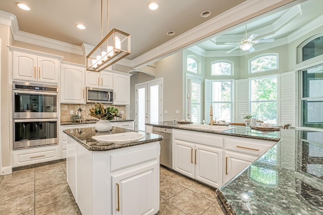 218 W Hubert Ct, Fresno, CA 93711 - kitchen with stainless steel appliances, crown molding, a kitchen island, backsplash, and white cabinetry