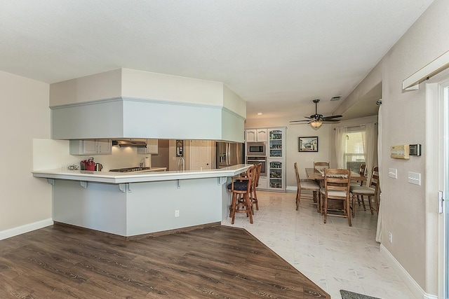 4950 W Minarets Ave, Fresno, CA 93722 - kitchen featuring appliances with stainless steel finishes, a breakfast bar area, a ceiling fan, a peninsula, and under cabinet range hood