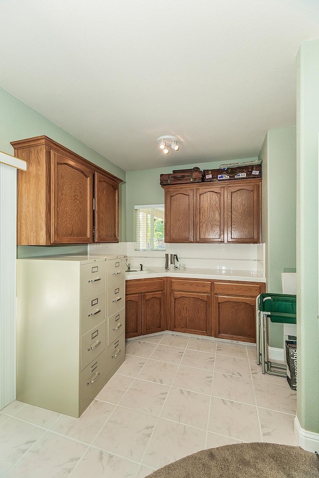 4950 W Minarets Ave, Fresno, CA 93722 - kitchen with light countertops, brown cabinets, light marble finish floors, and tasteful backsplash