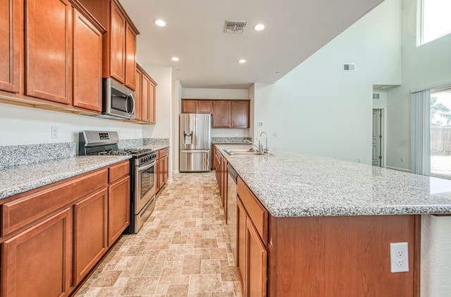 2354 S Garden, Fresno, CA 93725 - kitchen with stainless steel appliances, brown cabinets, a kitchen island with sink, recessed lighting, and light stone counters