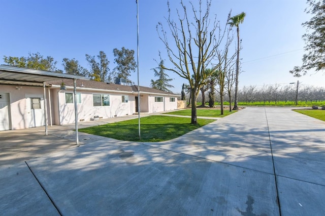 5942 S Cedar Ave, Fresno, CA 93725 - view of front of house with stucco siding, a front lawn, and concrete driveway