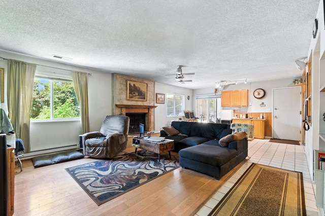 36358 Orange Grove Ave, Madera, CA 93636 - living room with a large fireplace, a ceiling fan, light wood-type flooring, a textured ceiling, and a baseboard heating unit