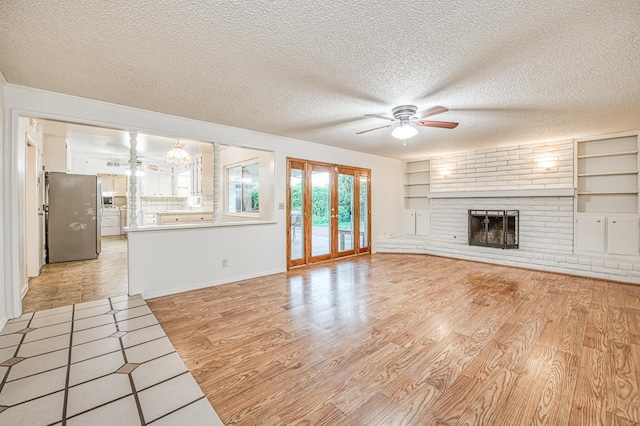 7343 N 4th St, Fresno, CA 93720 - unfurnished living room featuring ceiling fan, light wood-style flooring, a textured ceiling, a fireplace, and built in shelves
