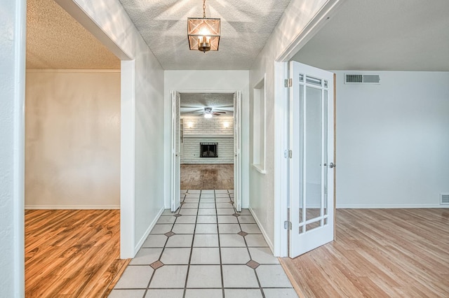 7343 N 4th St, Fresno, CA 93720 - hallway featuring a textured ceiling, light wood-style flooring, and a chandelier