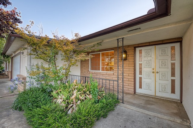 7343 N 4th St, Fresno, CA 93720 - view of exterior entry featuring covered porch, a garage, stucco siding, and brick siding