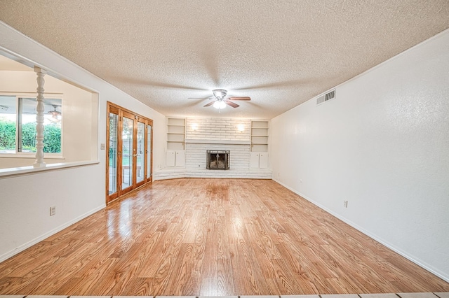 7343 N 4th St, Fresno, CA 93720 - unfurnished living room with a ceiling fan, wood finished floors, built in shelves, a brick fireplace, and a textured ceiling