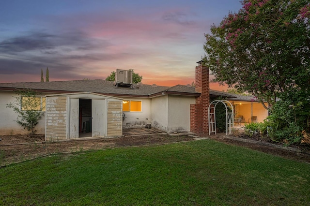 7343 N 4th St, Fresno, CA 93720 - back of house at dusk with a yard, stucco siding, and a chimney