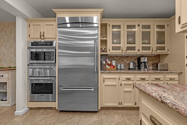 36522 Mudge Ranch Rd, Coarsegold, CA 93614 - kitchen featuring stainless steel appliances, a warming drawer, backsplash, light stone counters, and glass insert cabinets