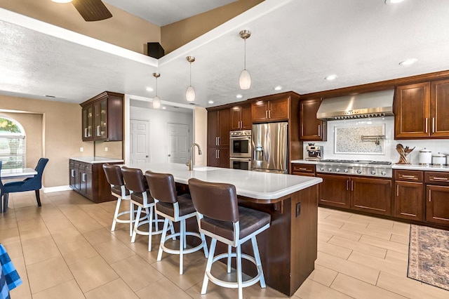 6421 S Greenwood Ave, Del Rey, CA 93616 - kitchen with appliances with stainless steel finishes, exhaust hood, light countertops, a kitchen island with sink, and a breakfast bar
