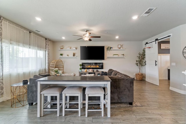6236 E Garland Ave, Fresno, CA 93727 - living room with a barn door, ceiling fan, wood finished floors, recessed lighting, and a glass covered fireplace