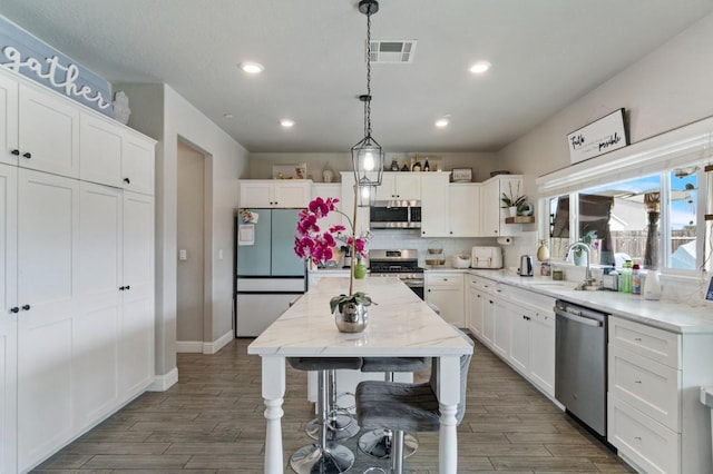 6236 E Garland Ave, Fresno, CA 93727 - kitchen with stainless steel appliances, wood finished floors, white cabinetry, recessed lighting, and backsplash