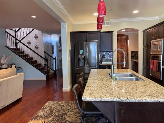 2291 E Prestwick Ave, Fresno, CA 93730 - kitchen featuring stainless steel appliances, arched walkways, light stone counters, dark wood-style floors, and crown molding
