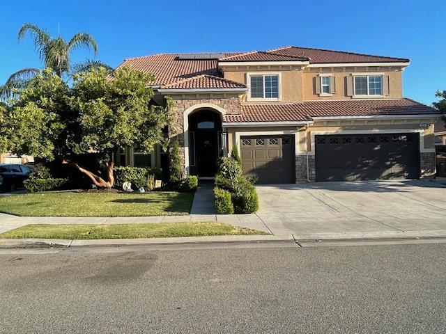 2291 E Prestwick Ave, Fresno, CA 93730 - mediterranean / spanish-style house with stone siding, a tiled roof, and driveway