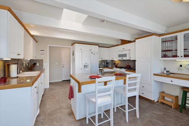 39397 Moonray Ln, Oakhurst, CA 93644 - kitchen with white appliances, decorative backsplash, a kitchen breakfast bar, white cabinets, and glass insert cabinets