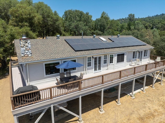 39397 Moonray Ln, Oakhurst, CA 93644 - back of house with a wooden deck, roof with shingles, roof mounted solar panels, a chimney, and a wooded view