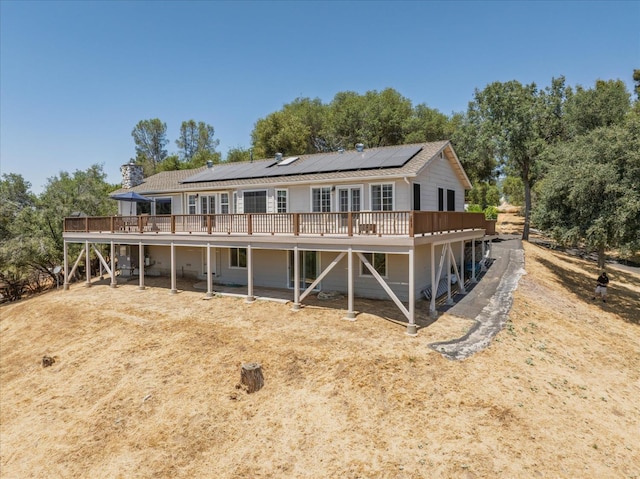 39397 Moonray Ln, Oakhurst, CA 93644 - back of house featuring a deck, roof mounted solar panels, and view of wooded area