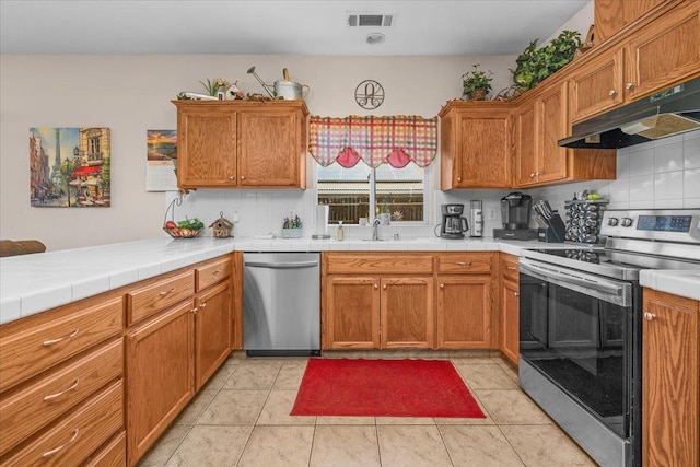 6164 W Keats, Fresno, CA 93723 - kitchen featuring appliances with stainless steel finishes, decorative backsplash, under cabinet range hood, and a peninsula