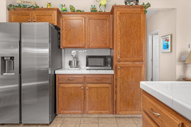 6164 W Keats, Fresno, CA 93723 - kitchen featuring appliances with stainless steel finishes, backsplash, tile countertops, and brown cabinets