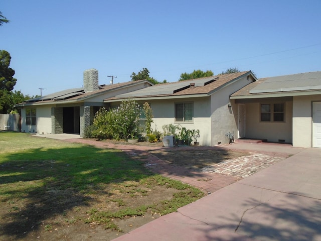 935 S Park Circle Dr, Fresno, CA 93727 - ranch-style house featuring stucco siding, solar panels, a front lawn, and a chimney