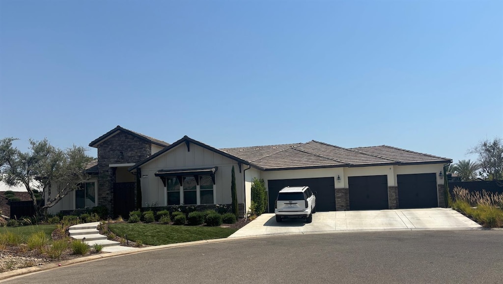 2189 E Strathspey Way, Fresno, CA 93730 - view of front facade with stone siding, concrete driveway, a garage, and board and batten siding